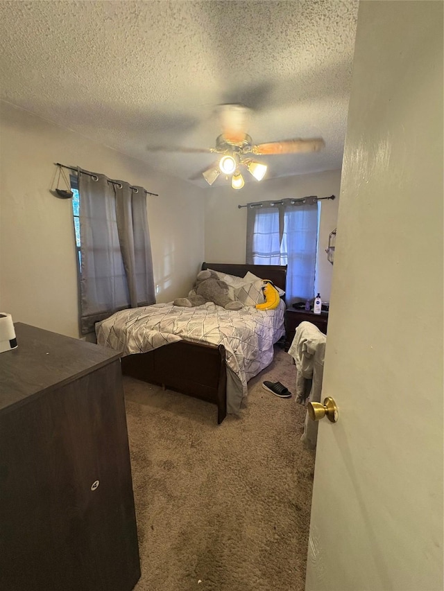 carpeted bedroom with ceiling fan and a textured ceiling