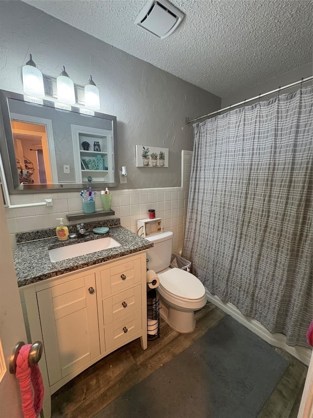 bathroom featuring tile walls, hardwood / wood-style flooring, vanity, toilet, and a textured ceiling