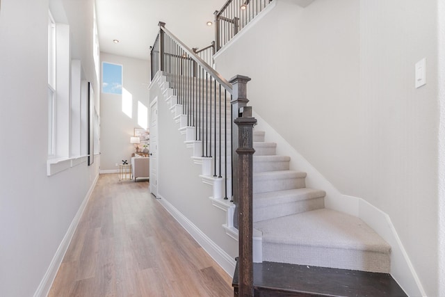 stairway featuring hardwood / wood-style flooring and a towering ceiling