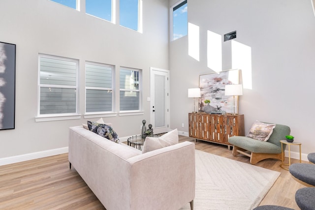 living room featuring a towering ceiling and light hardwood / wood-style flooring