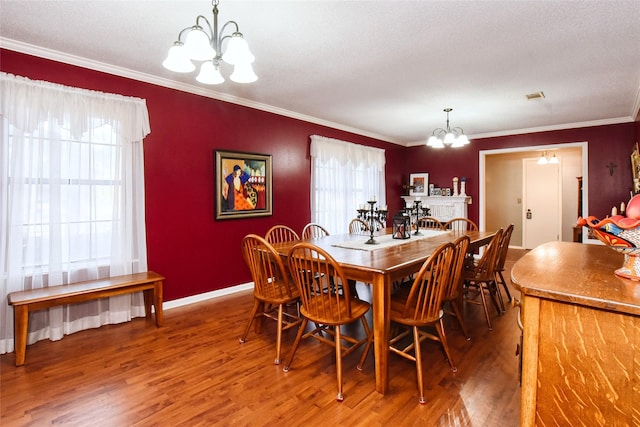 dining space with wood-type flooring, a textured ceiling, an inviting chandelier, and crown molding