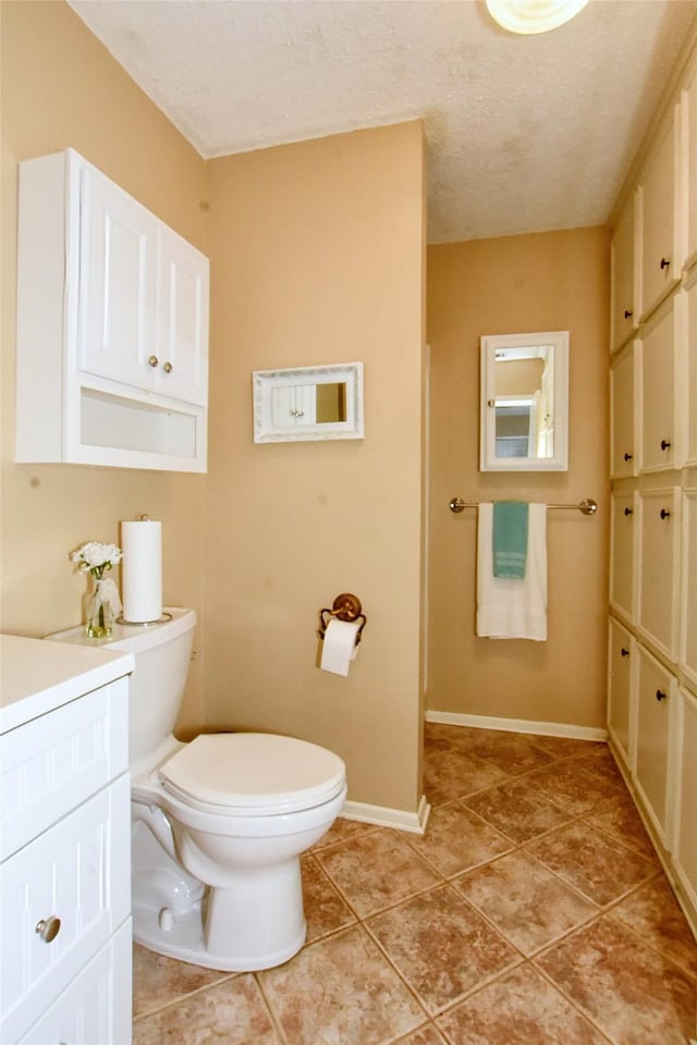 bathroom with toilet, vanity, a textured ceiling, and tile patterned floors