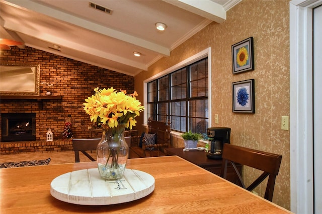 dining area with a fireplace, wood-type flooring, lofted ceiling with beams, and ornamental molding