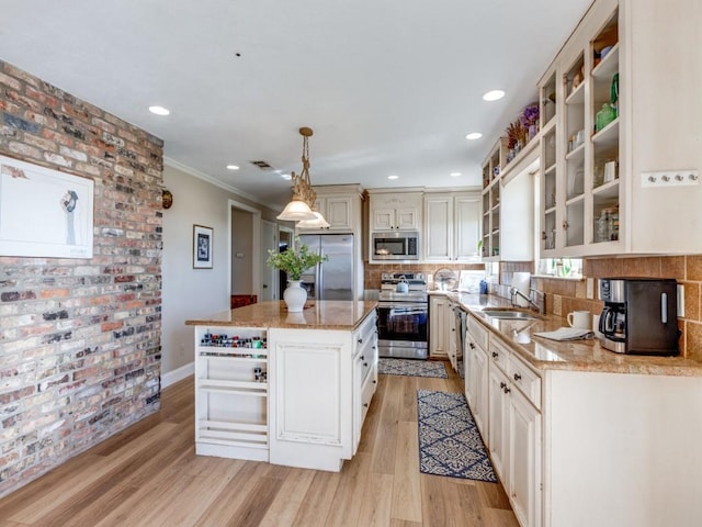 kitchen featuring a center island, sink, light wood-type flooring, appliances with stainless steel finishes, and decorative light fixtures