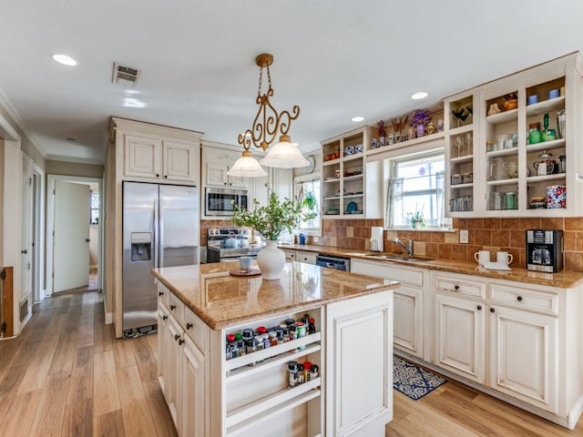 kitchen with a kitchen island, light hardwood / wood-style floors, stainless steel appliances, and hanging light fixtures