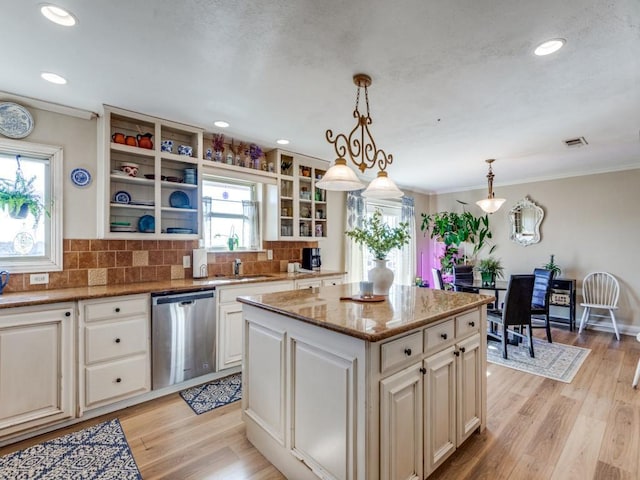 kitchen featuring tasteful backsplash, stainless steel dishwasher, decorative light fixtures, light hardwood / wood-style floors, and a kitchen island