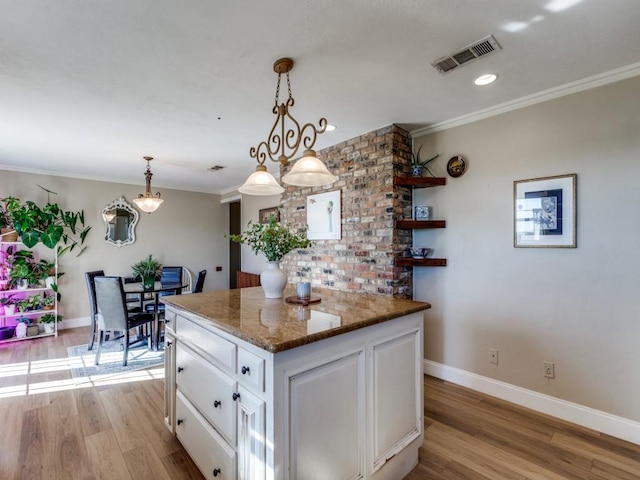 kitchen with white cabinets, a center island, light wood-type flooring, and crown molding