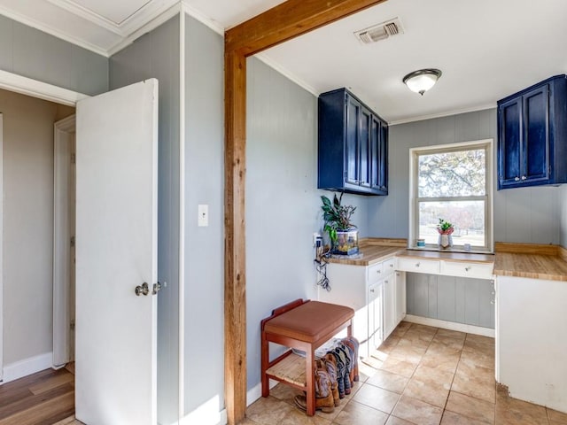 kitchen featuring blue cabinetry, crown molding, and light tile patterned flooring