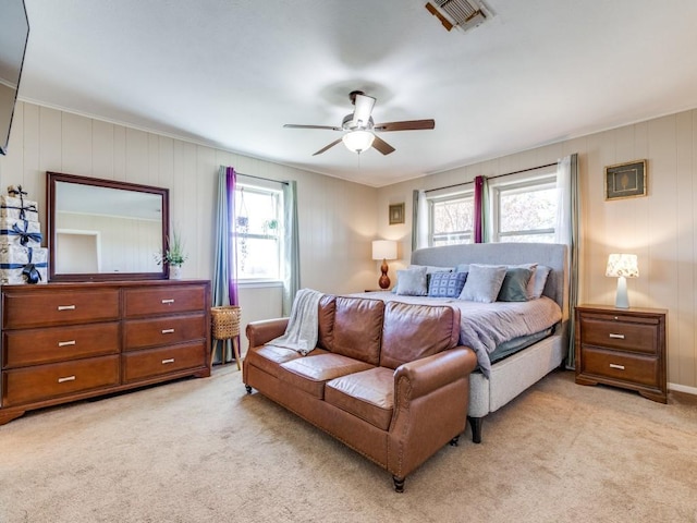 bedroom with ceiling fan, light colored carpet, and multiple windows