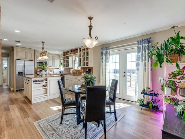 dining space with french doors, light wood-type flooring, and ornamental molding