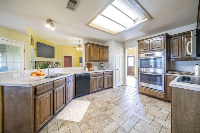 kitchen with sink, kitchen peninsula, ceiling fan, black dishwasher, and stainless steel double oven