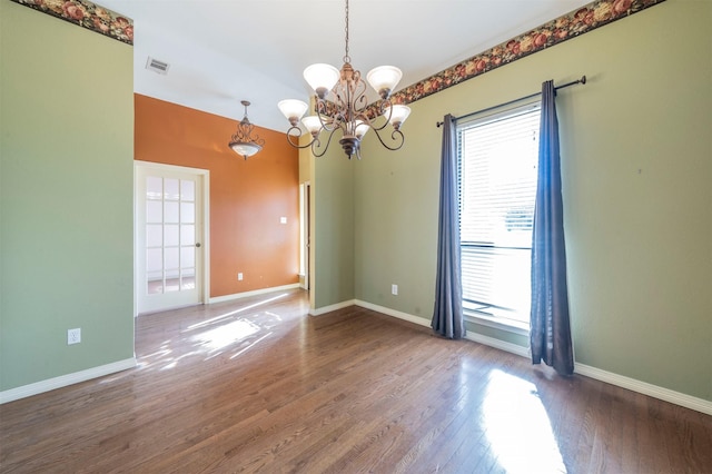 spare room with hardwood / wood-style flooring and a chandelier