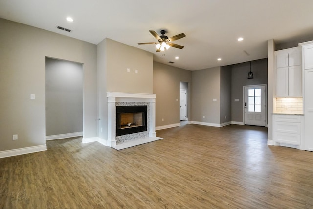 unfurnished living room featuring a premium fireplace, hardwood / wood-style floors, and ceiling fan