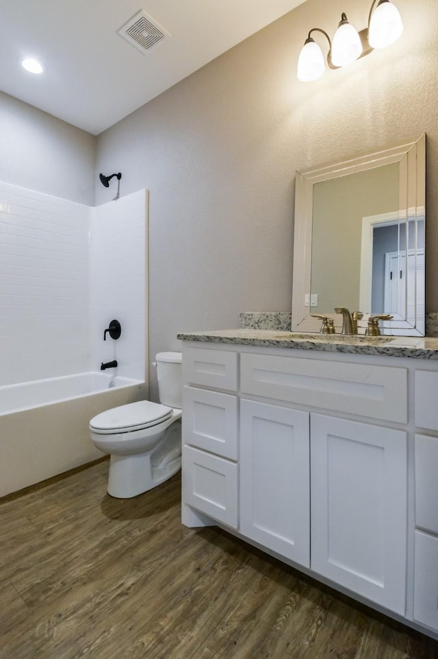 full bathroom featuring hardwood / wood-style flooring, vanity, toilet, and tub / shower combination