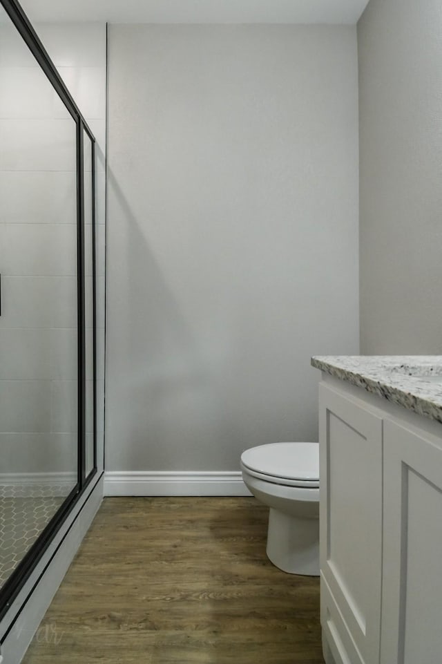 bathroom with a shower with door, wood-type flooring, vanity, and toilet