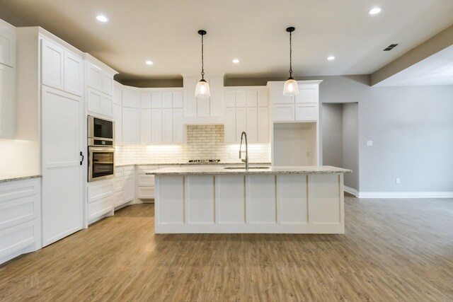 kitchen featuring light hardwood / wood-style floors, white cabinetry, a kitchen island with sink, and sink