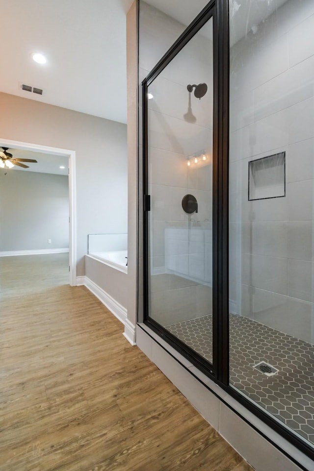 bathroom featuring hardwood / wood-style flooring, ceiling fan, and separate shower and tub