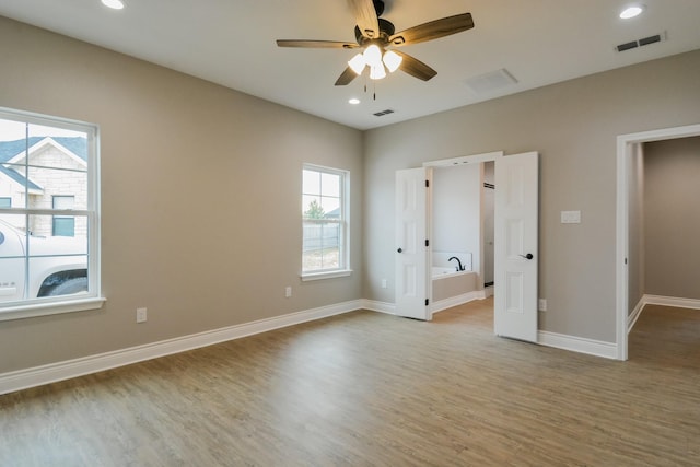 unfurnished bedroom featuring ensuite bathroom, ceiling fan, and light hardwood / wood-style flooring