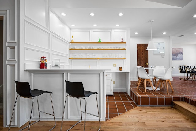 kitchen featuring tile patterned flooring, a breakfast bar, white cabinetry, and hanging light fixtures