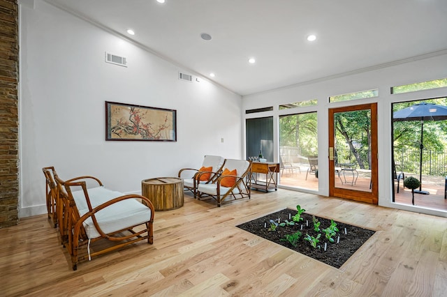 living area with light wood-type flooring, crown molding, and high vaulted ceiling