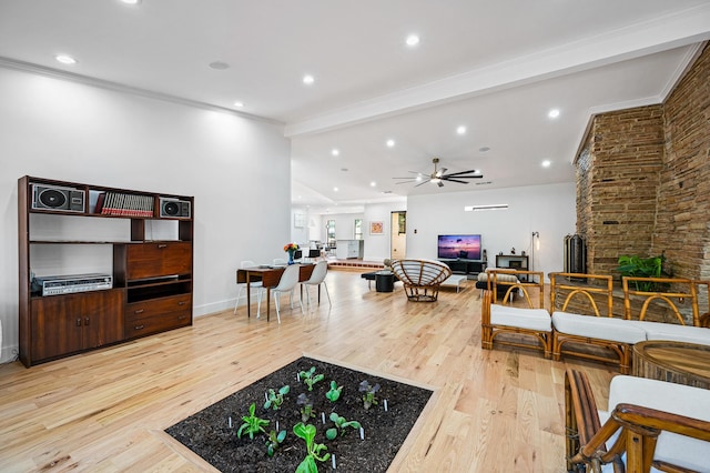 living room with crown molding, ceiling fan, a fireplace, beamed ceiling, and light hardwood / wood-style floors