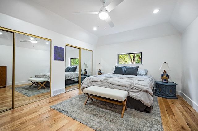 bedroom with hardwood / wood-style floors, multiple closets, ceiling fan, and lofted ceiling