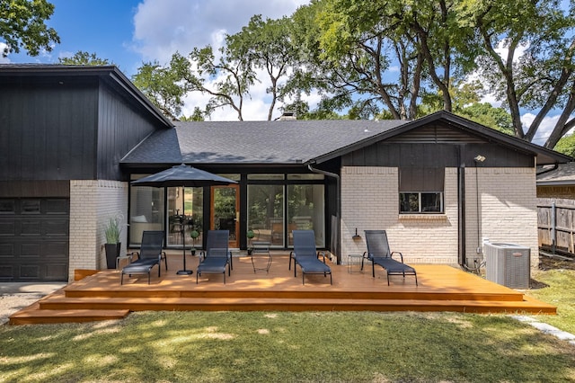 back of property with a deck, a lawn, a garage, and central air condition unit