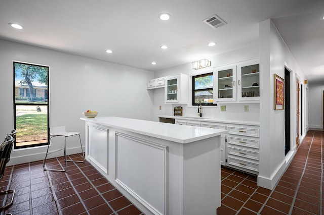 kitchen with white cabinets, dark tile patterned floors, and sink