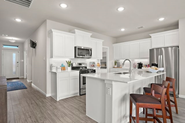 kitchen featuring sink, appliances with stainless steel finishes, a breakfast bar, white cabinets, and light wood-type flooring