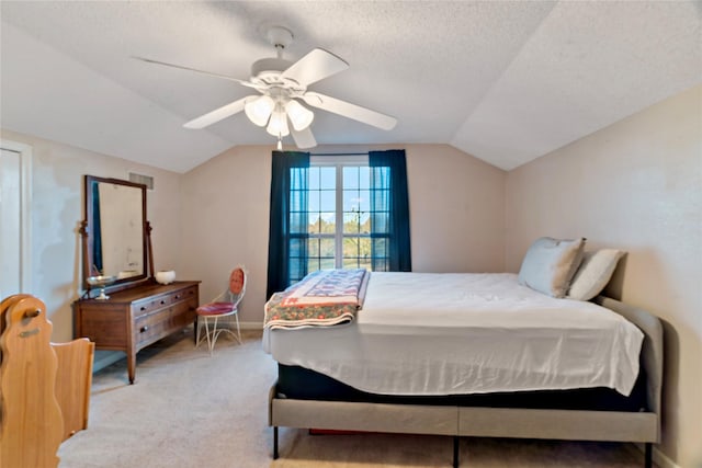 bedroom featuring ceiling fan, light colored carpet, lofted ceiling, and a textured ceiling