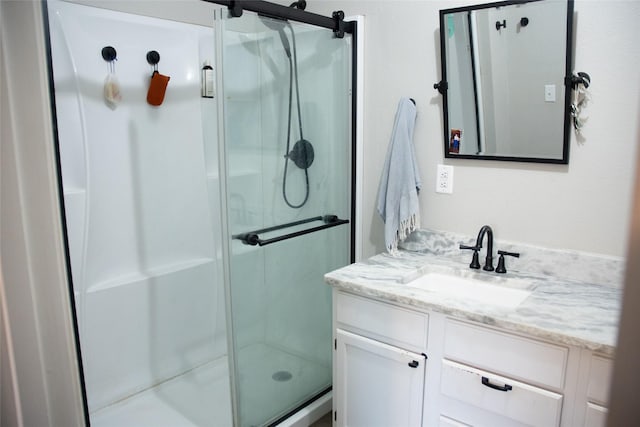 bathroom featuring a shower with door and vanity