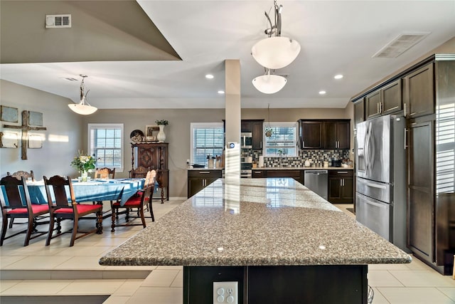 kitchen with a large island, backsplash, pendant lighting, and stainless steel appliances