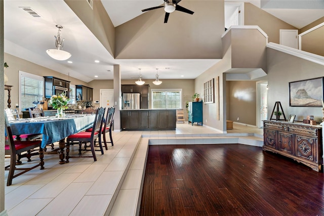 dining area with ceiling fan, high vaulted ceiling, and light wood-type flooring