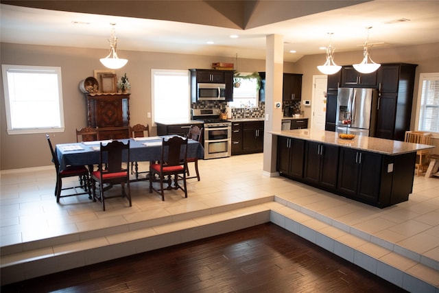 kitchen featuring hanging light fixtures, a center island, stainless steel appliances, and light hardwood / wood-style floors