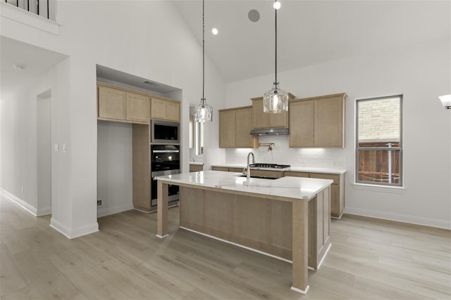 kitchen featuring built in microwave, light brown cabinets, high vaulted ceiling, pendant lighting, and a center island with sink