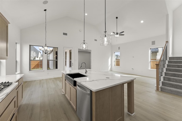 kitchen with ceiling fan with notable chandelier, light hardwood / wood-style flooring, stainless steel dishwasher, and sink