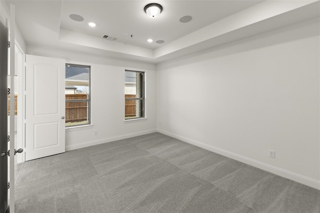 carpeted spare room with a raised ceiling