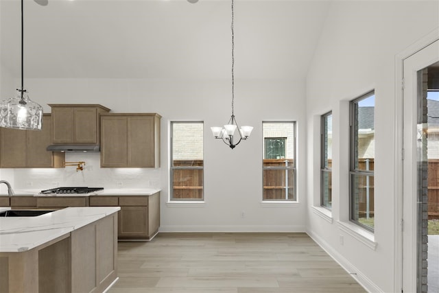 kitchen with a wealth of natural light, light hardwood / wood-style flooring, pendant lighting, and stainless steel gas stovetop