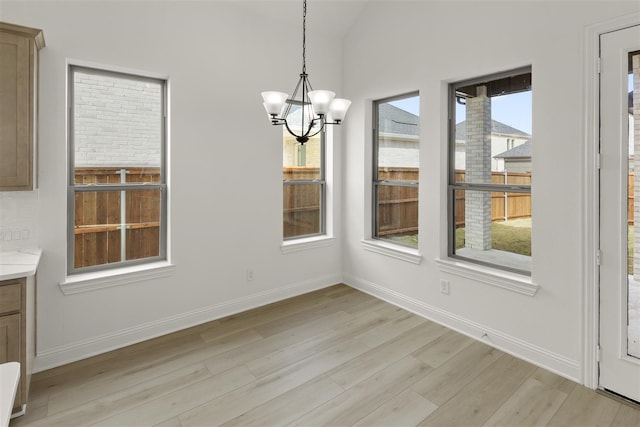 unfurnished dining area with light hardwood / wood-style flooring, plenty of natural light, and a notable chandelier