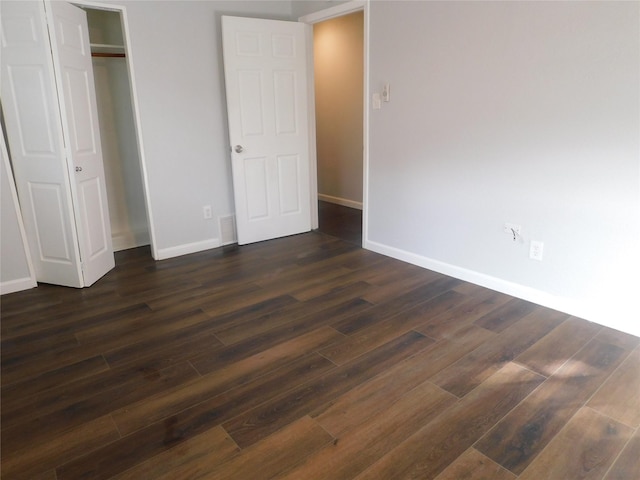 unfurnished bedroom with dark hardwood / wood-style floors and a closet