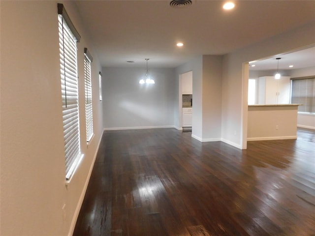 unfurnished living room featuring dark hardwood / wood-style flooring and an inviting chandelier