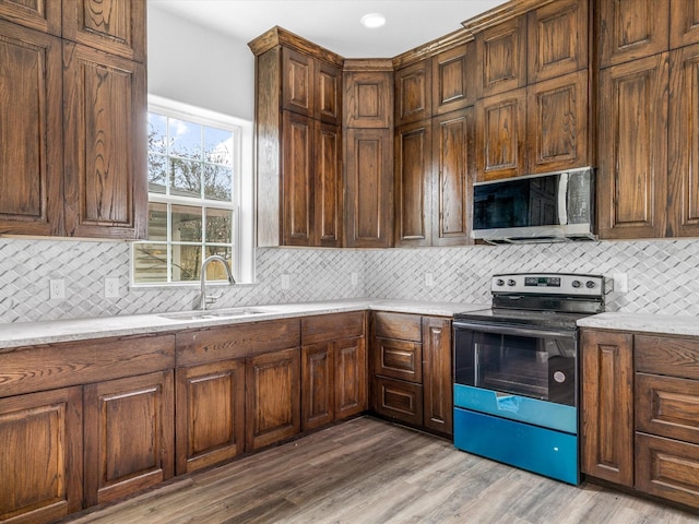 kitchen with hardwood / wood-style flooring, backsplash, sink, and stainless steel appliances