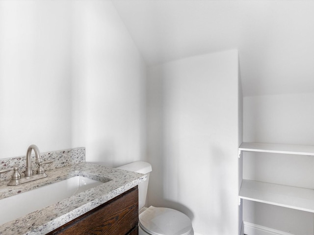 bathroom featuring vanity, toilet, and lofted ceiling