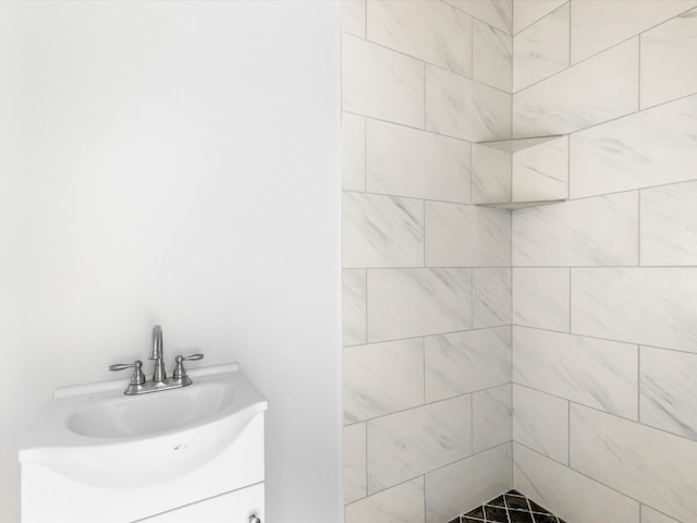 bathroom with a tile shower and vanity