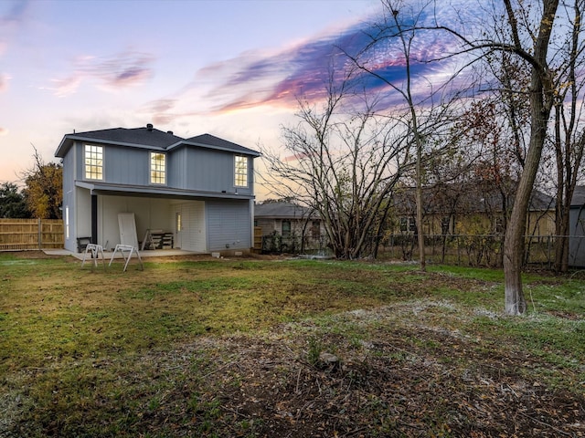 back house at dusk featuring a yard and a patio area