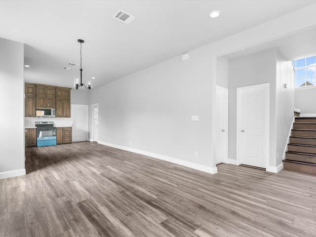 unfurnished living room featuring hardwood / wood-style floors and a chandelier