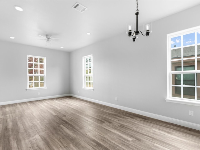 spare room featuring light hardwood / wood-style floors and ceiling fan with notable chandelier