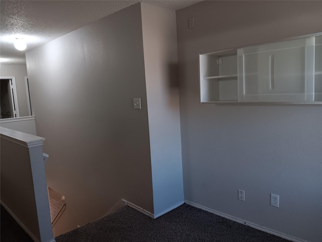 interior space with a textured ceiling and dark colored carpet