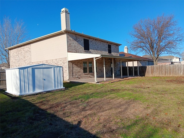 rear view of house featuring a patio, a lawn, and a shed