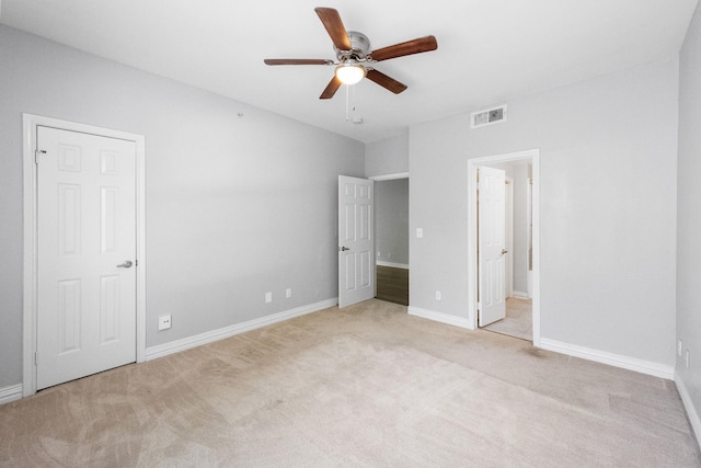 unfurnished bedroom with visible vents, baseboards, ceiling fan, ensuite bathroom, and light colored carpet